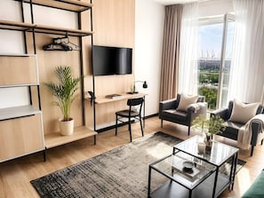 A modern living room with a flat-screen TV, a sofa, a coffee table, and a potted plant. - Old Town Heart - National Stadium Tower 74 (Warsaw)
