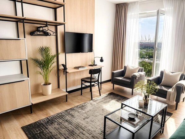 Ein modernes Wohnzimmer mit Flachbildfernseher, Sofa, Couchtisch und einer Topfpflanze.