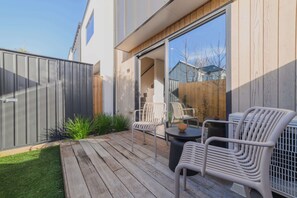 Eine moderne Terrasse im Freien mit Holzterrasse, Metallstühlen und einem runden Tisch.