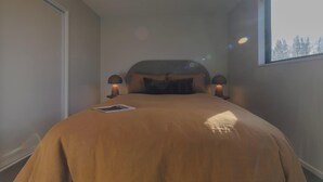 A bedroom with a bed, two bedside lamps, a window, and a view of trees. - Modern 1BR Near Christchurch CBD & Cashel Street (Christchurch)