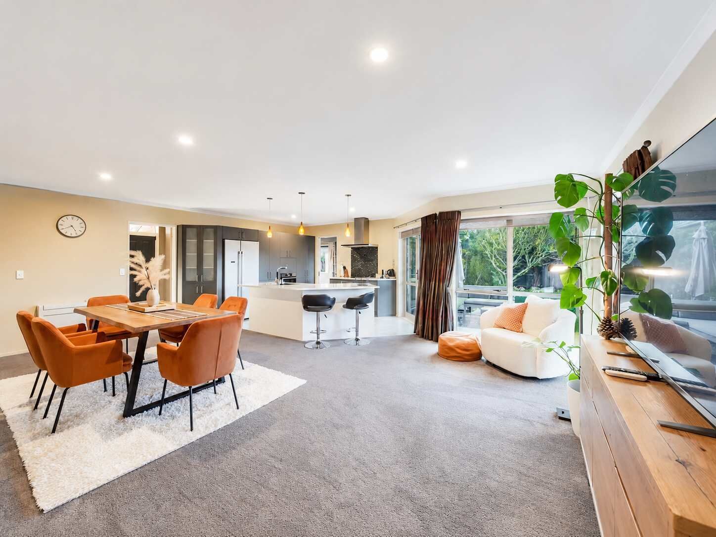 A modern living space with a dining area, kitchen, and seating area.