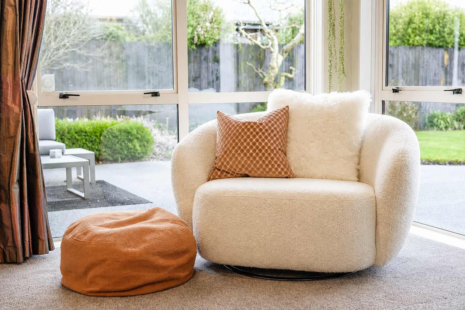 Un salon chaleureux avec un fauteuil moelleux, un pouf assorti et un coussin décoratif à motifs.