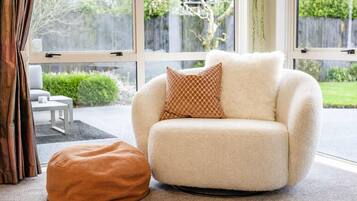 A cozy living room with a plush armchair, a matching ottoman, and a patterned throw pillow.