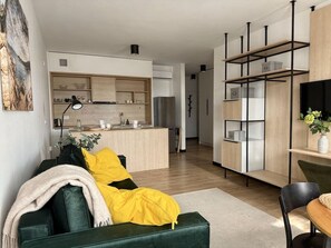 A modern living room with a green sofa, a yellow blanket, and a dining area with a table and chairs. - Old Town Heart - National Stadium Tower 44 (Warsaw)