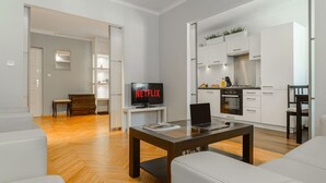 Ein modernes Wohnzimmer mit einem Flachbildfernseher, einem Laptop auf einer Glastisch und einem Sofa.