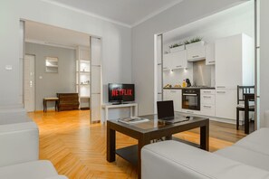 Ein modernes Wohnzimmer mit einem Flachbildfernseher, einem Laptop auf einer Glastisch und einem Sofa.
