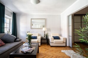 A modern living room with a sofa, two armchairs, a coffee table, a side table, a lamp, a mirror, and a potted plant. - OldTownHeart XVII -Freta Luxury (Warsaw)