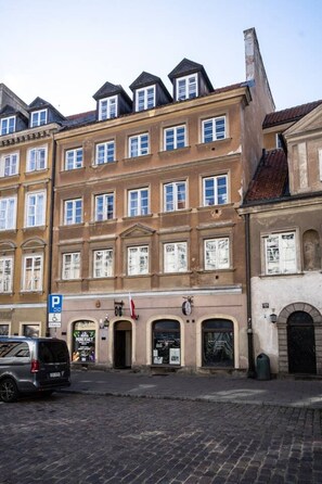 A multi-story building with a ground-floor shop and a parking sign. - OldTownHeart XVII -Freta Luxury (Warsaw)