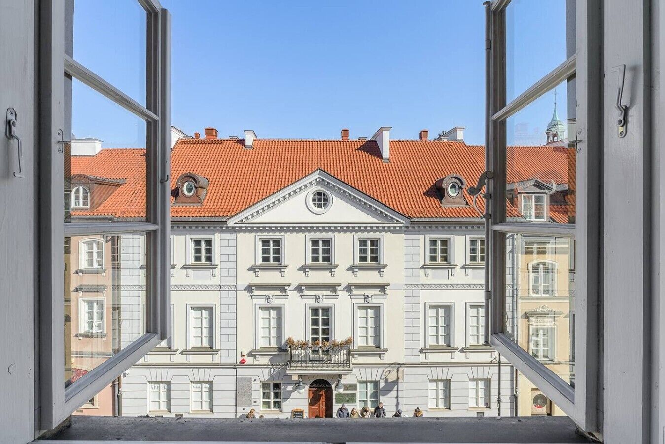 Une vue d’un bâtiment classique à la façade symétrique, doté de nombreuses fenêtres et d’une entrée centrale.