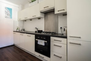 Une cuisine moderne avec des meubles blancs, une cuisinière noire et un dosseret carrelé.