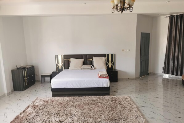 A bedroom with a bed, bedside tables, a dresser, a rug, and a chandelier.