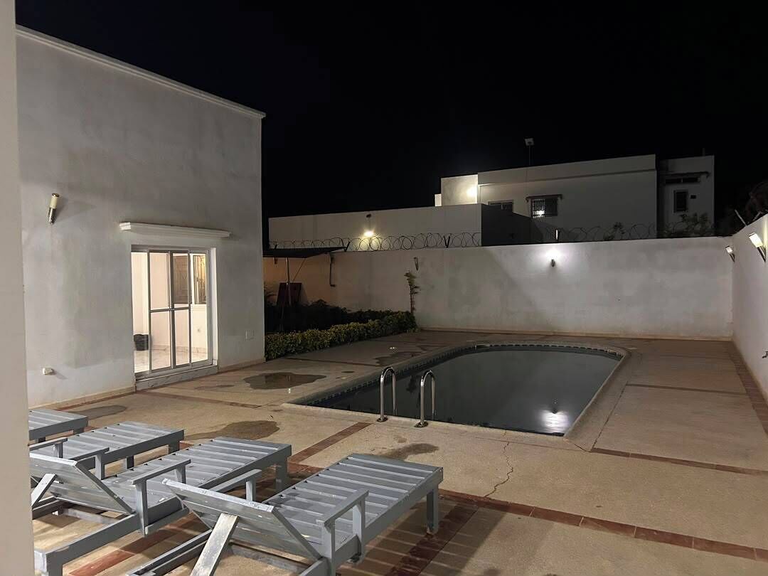 Un espace piscine aménagé sur le toit, offrant une vue dégagée sur le ciel, avec une piscine et quelques chaises longues.