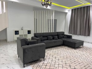 Una sala de estar moderna con un sofá seccional, una chaise longue y una alfombra estampada.