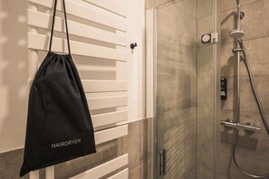 A bathroom with a glass shower enclosure, a towel rack, and a black bag hanging on the wall. - Kiez Studio for 2 Guests in Berlin Neukölln (Berlin)