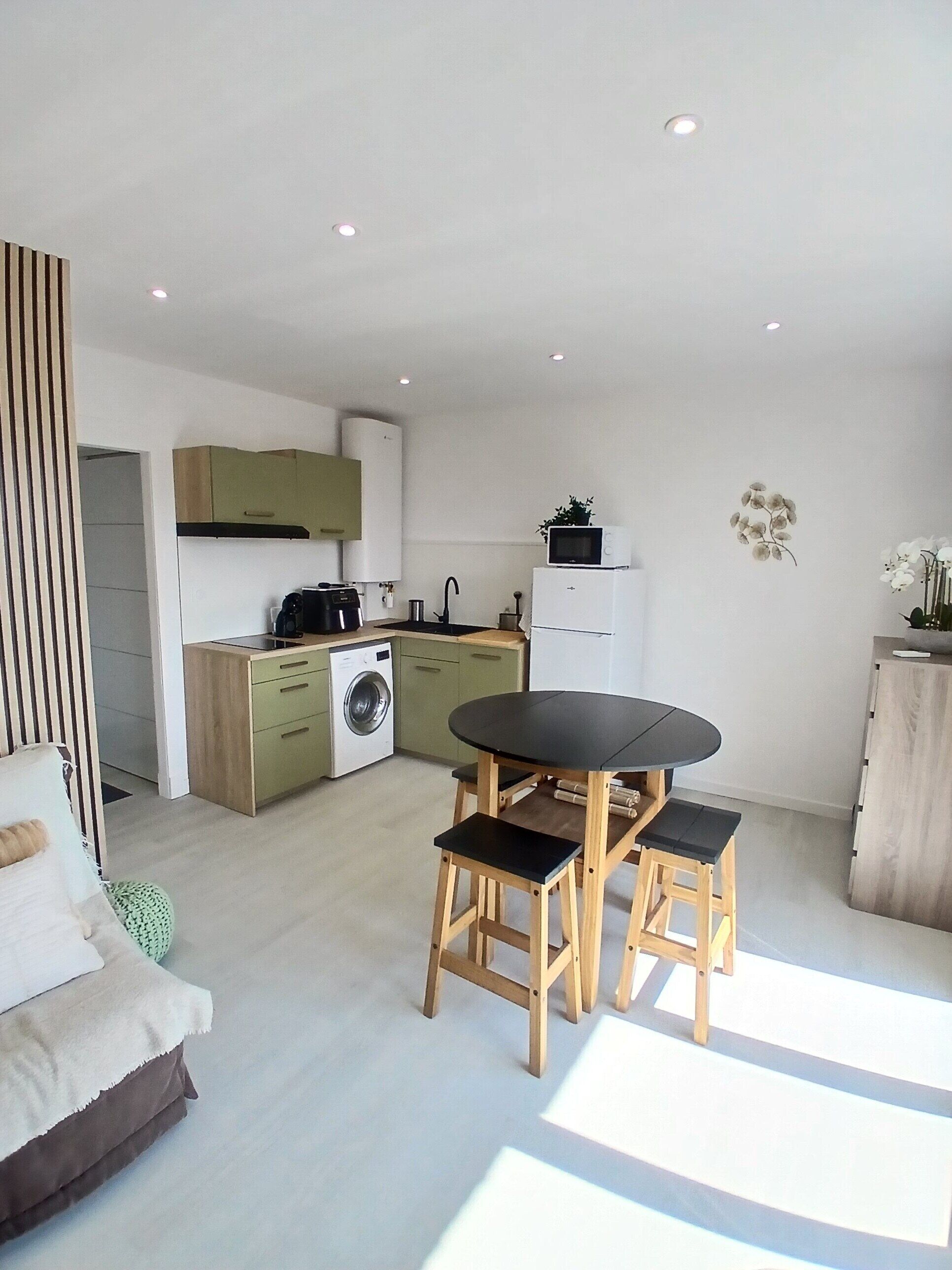 Una cocina moderna con comedor, que incluye una mesa, sillas, lavadora y refrigerador.