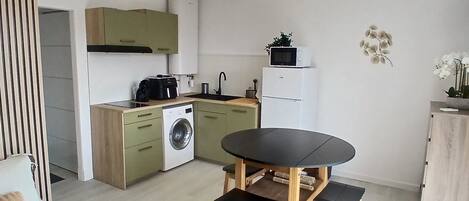 Uma cozinha moderna com área de refeições, incluindo uma mesa e cadeiras, uma máquina de lavar e uma geladeira.