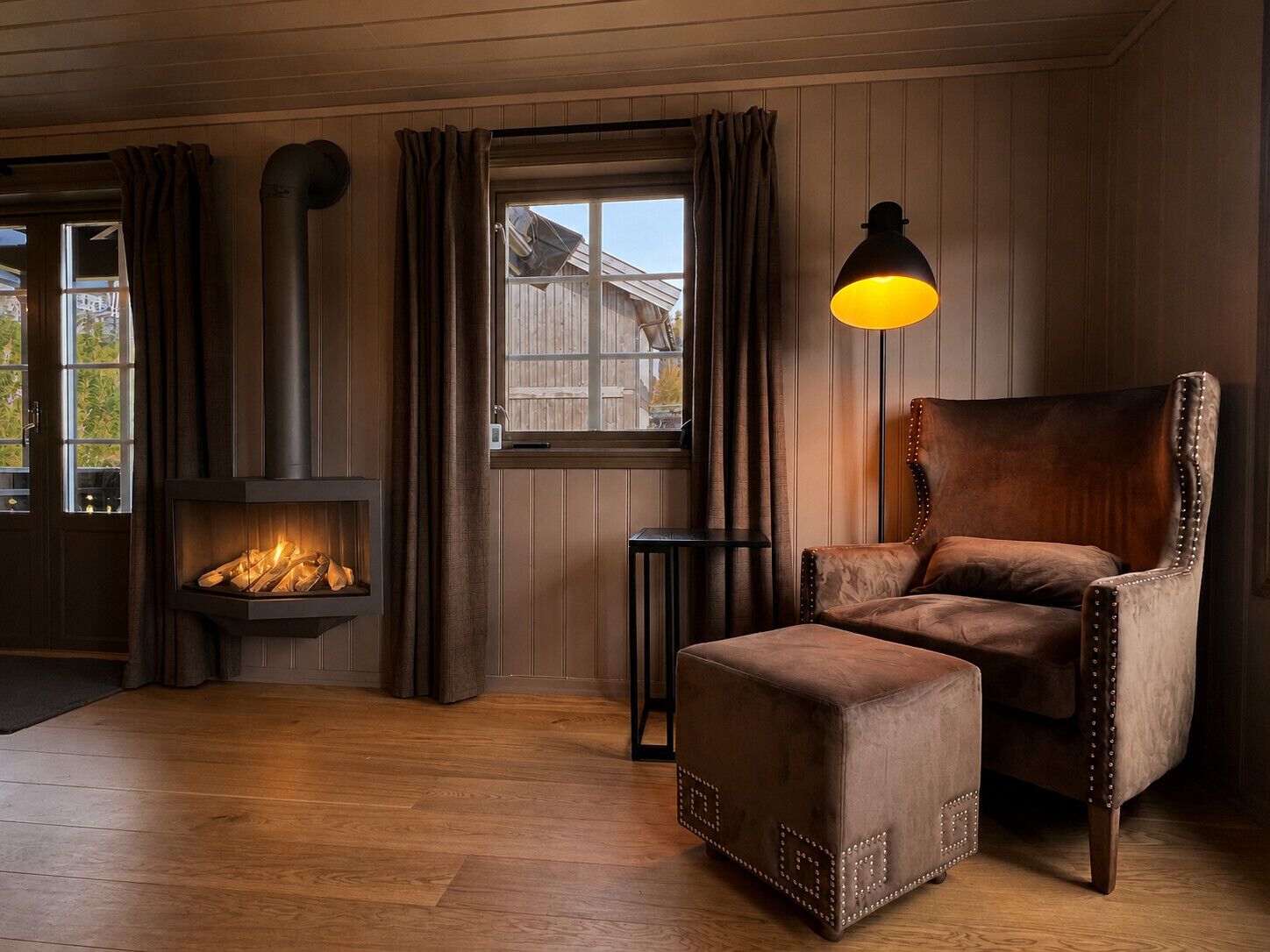 Una habitación acogedora con chimenea, un sillón de cuero y un pequeño reposapiés.
