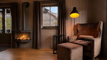 Una habitación acogedora con chimenea, un sillón de cuero y un pequeño reposapiés.