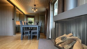 Un interior moderno con una zona de comedor, una chimenea y una cocina al fondo.