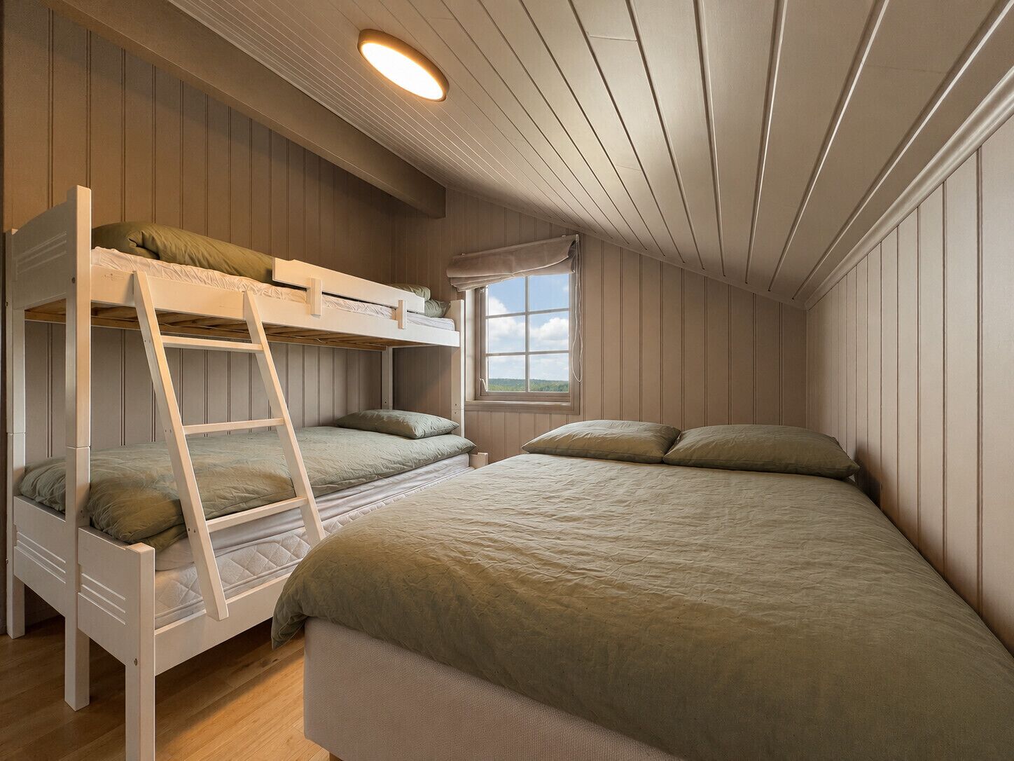 A room with bunk beds, a window with a view, and a ceiling light.
