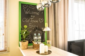 A room with a chalkboard wall displaying a welcome message, a potted plant, two candles, and a lamp. - Old Town Heart XXI- Pl.Teatralny (Warsaw)