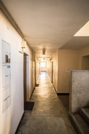 A long, narrow hallway with a series of doors on one side and a staircase on the other. - Old Town Heart XXI- Pl.Teatralny (Warsaw)