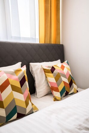 A bed with two pillows, one plain and one patterned, in a room with a window and curtains. - Old Town Heart XXI- Pl.Teatralny (Warsaw)
