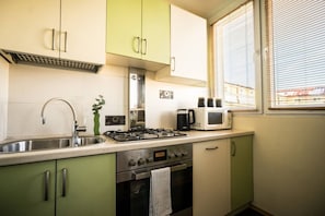 A compact kitchen with a gas stove, a microwave, and a sink. - Old Town Heart XXI- Pl.Teatralny (Warsaw)