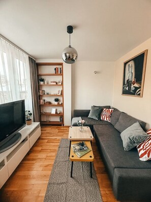 A modern living room with a flat-screen TV, a bookshelf, a grey sofa, and a coffee table. - Old Town Heart XXI- Pl.Teatralny (Warsaw)