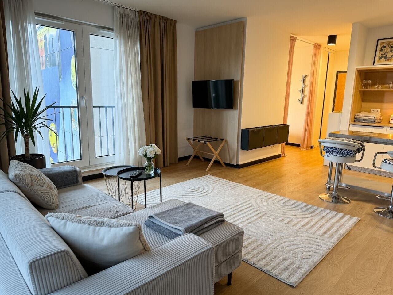 Ein modernes Wohnzimmer mit einer Couch, einem Couchtisch, einem Fernseher und einer Küchenzeile mit Barhocker.