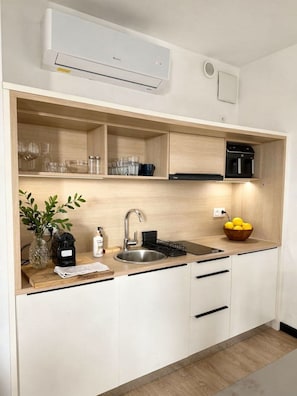 Ett modernt kök med en inbyggd diskmaskin, en diskho och en bänkskiva med en skål full av citroner.