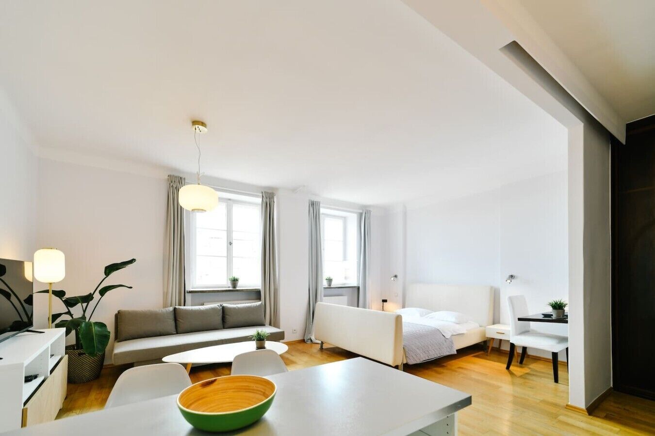 Un salon moderne et bien éclairé, avec un canapé, une table à manger et un lit.