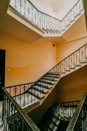 Ein mehrgeschossiges Interieur mit einer zentralen Treppe, verziert mit aufwendigen Metallgeländern und einem geschwungenen Design.