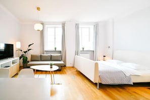 A modern living room with a flat-screen TV, a sofa, a coffee table, and a bed. - Old Town Heart V - Old Town Square (Warsaw)