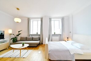 Une chambre d’hôtel moderne équipée d’un lit, d’un canapé, d’une petite table et d’un téléviseur.
