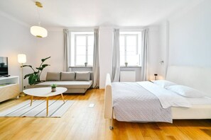 A modern hotel room with a bed, sofa, and a small table with a plant. - Old Town Heart V - Old Town Square (Warsaw)