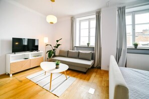 A modern living room with a sofa, a coffee table, a TV, and a window with curtains. - Old Town Heart V - Old Town Square (Warsaw)