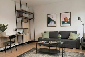 A modern living room with a grey sofa, a coffee table, a desk with a chair, a bookshelf, and two framed pictures on the wall. - Old Town Heart VI - Metro 100m - Stadion Narodowy (Warsaw)