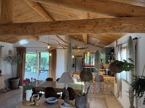 A rustic interior with exposed wooden beams, a dining area with a table and chairs, and hanging plants. - Stunning stone sheep barn, infinity pool (Lecci)