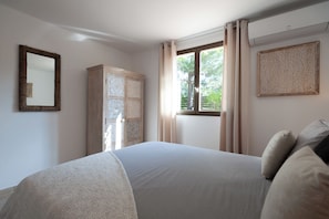 A bedroom with a bed, a wardrobe, a window with curtains, and a wall-mounted mirror. - Stunning stone sheep barn, infinity pool (Lecci)