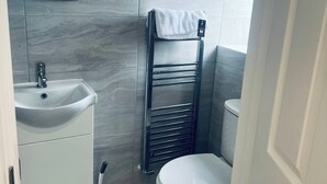 Un baño pequeño con un lavamanos blanco, un inodoro y un perchero para toallas.