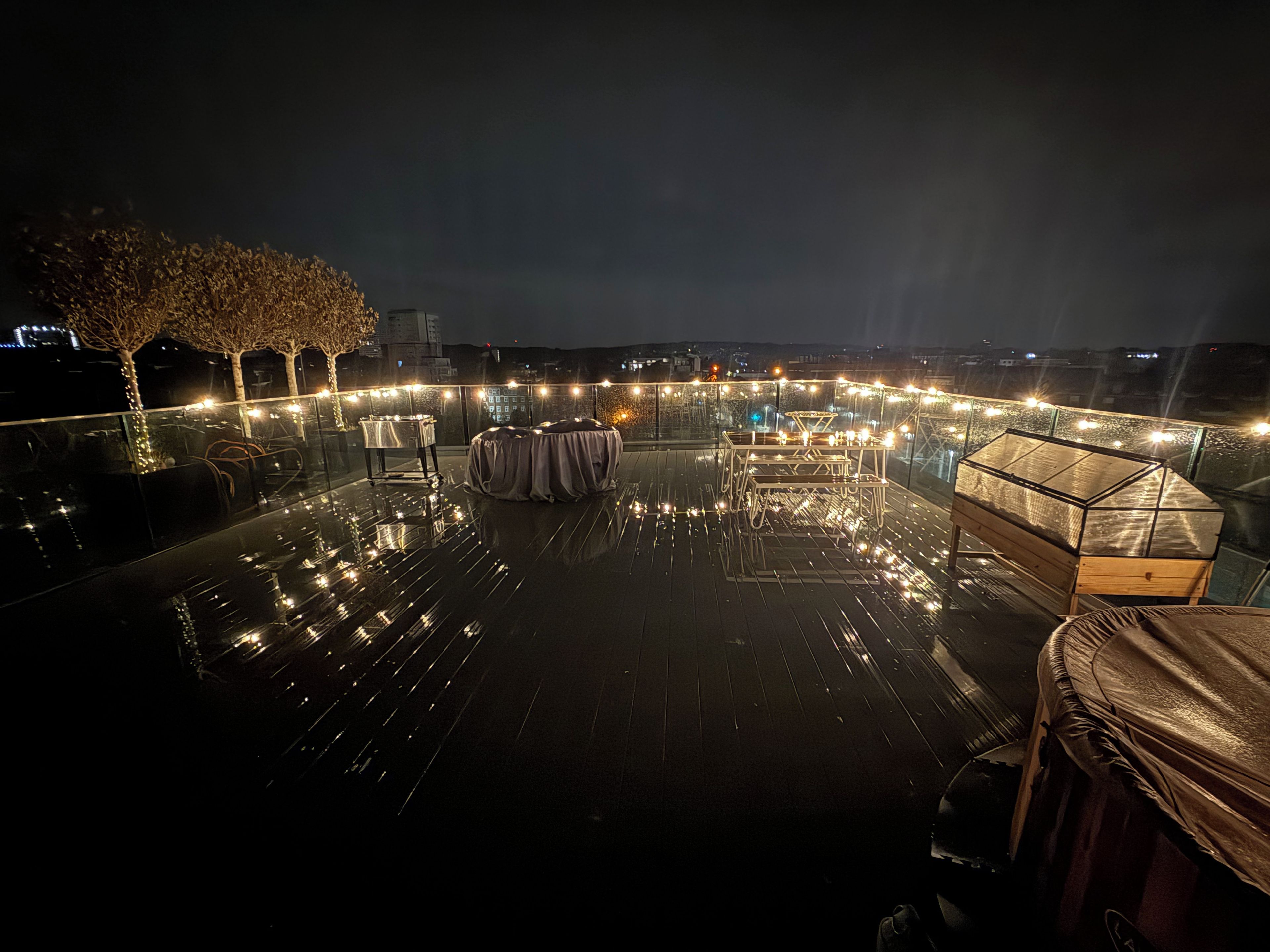 Une terrasse sur le toit, avec des tables, des chaises et des guirlandes lumineuses.