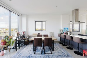 Une cuisine moderne avec un coin repas, de grandes fenêtres et une vue sur la ville.