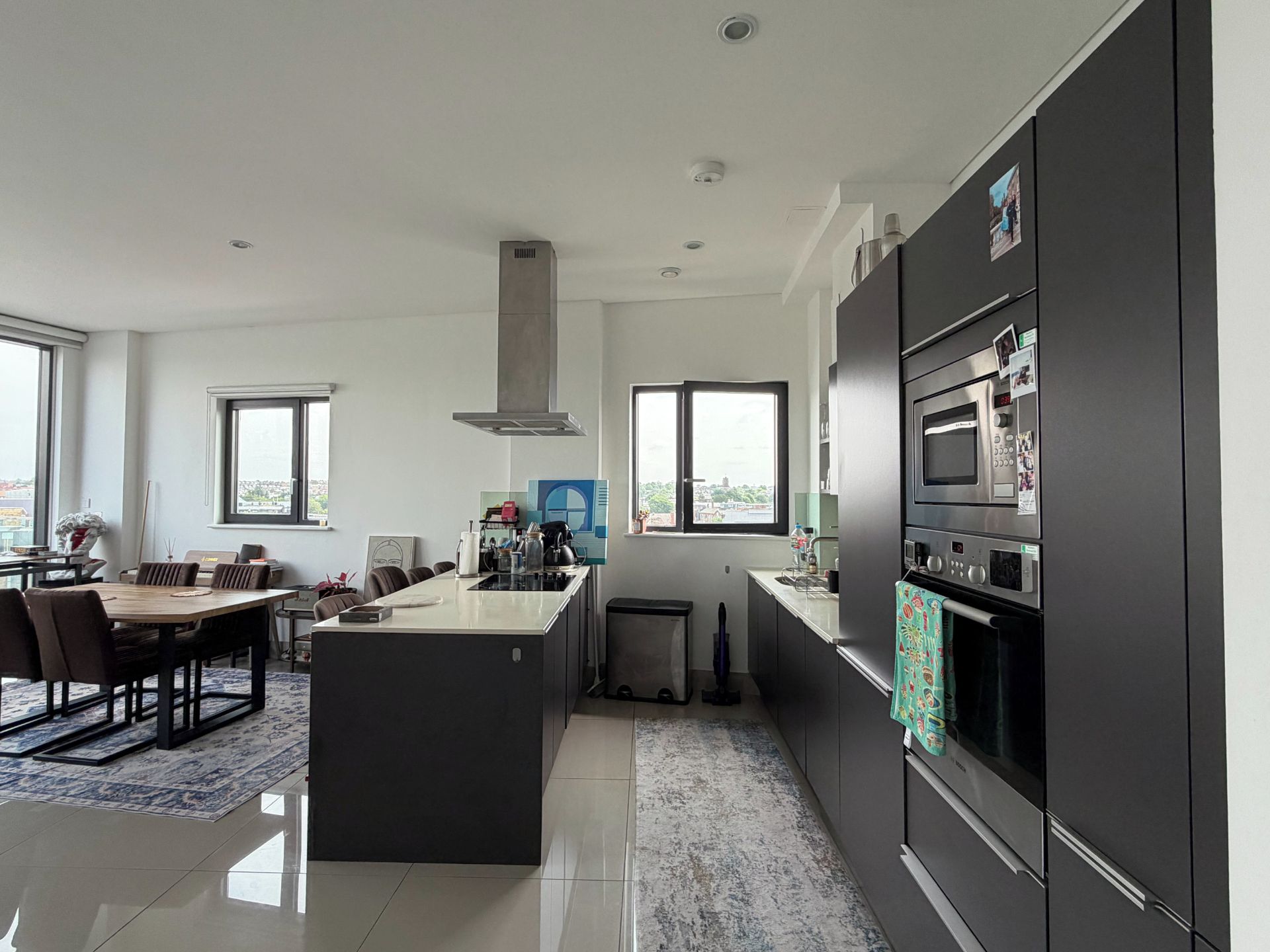 A modern kitchen with a central island, built-in appliances, and large windows.