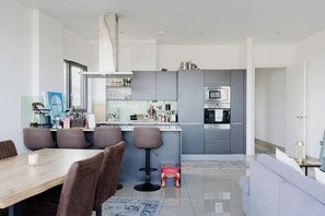 Une cuisine moderne avec des meubles gris, une hotte en acier inoxydable et un four encastré.