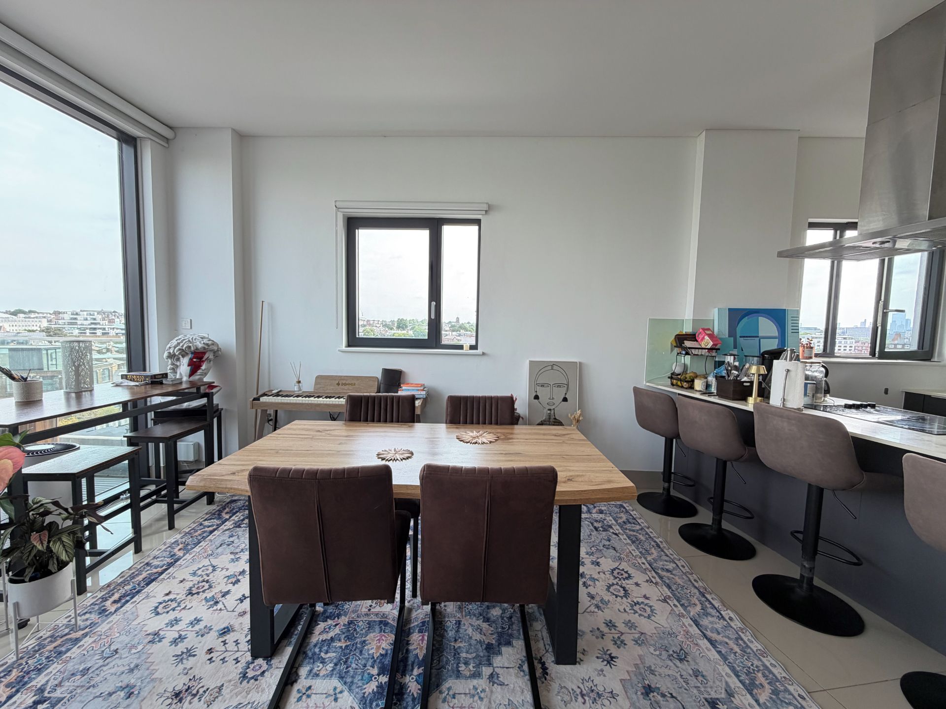A modern kitchen with a dining area, large windows, and a city view.