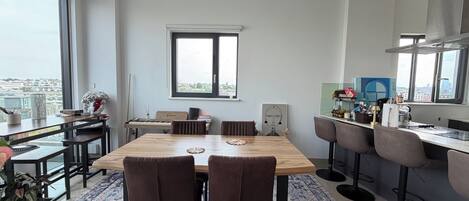 A modern kitchen with a dining area, large windows, and a city view.