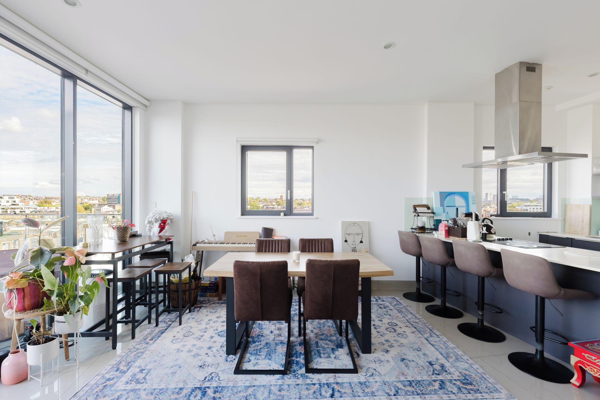 A modern kitchen with a dining area, large windows, and a city view.