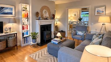 A living room with a fireplace, a sofa, a dining area, and a bookshelf.