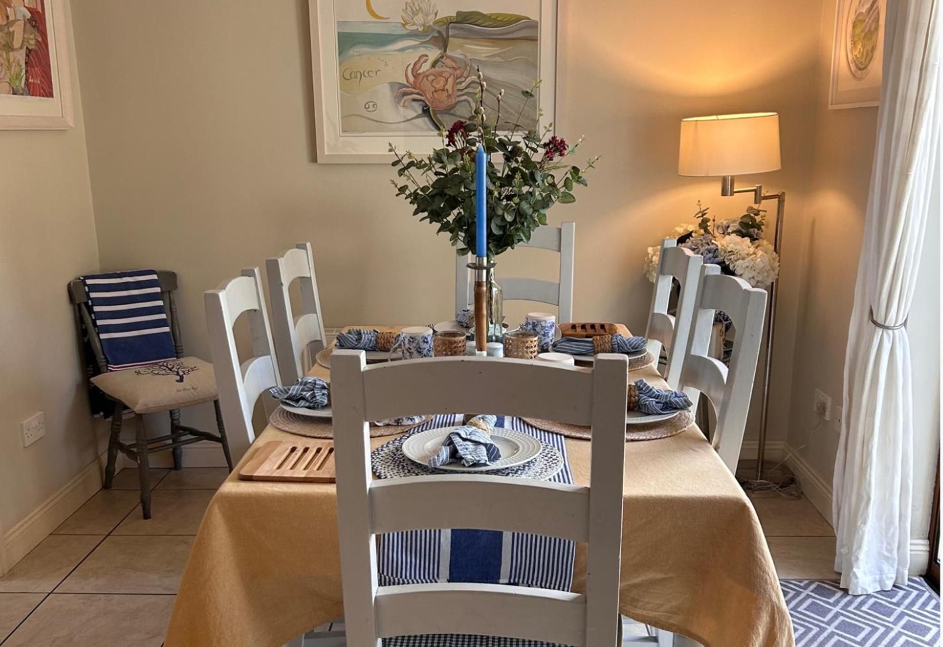 A dining area with a table set for four, surrounded by white chairs.